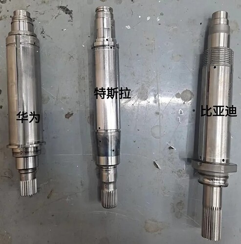Three metallic shafts, labeled in Chinese characters, are arranged on a gray surface. (由 AI 生成标题)