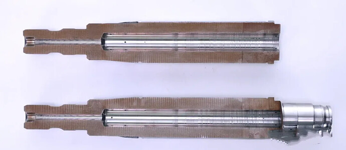 A high-angle, close-up view shows two disassembled metallic components, each with a long, slender rod housed within a segmented, textured casing. (由 AI 生成标题)